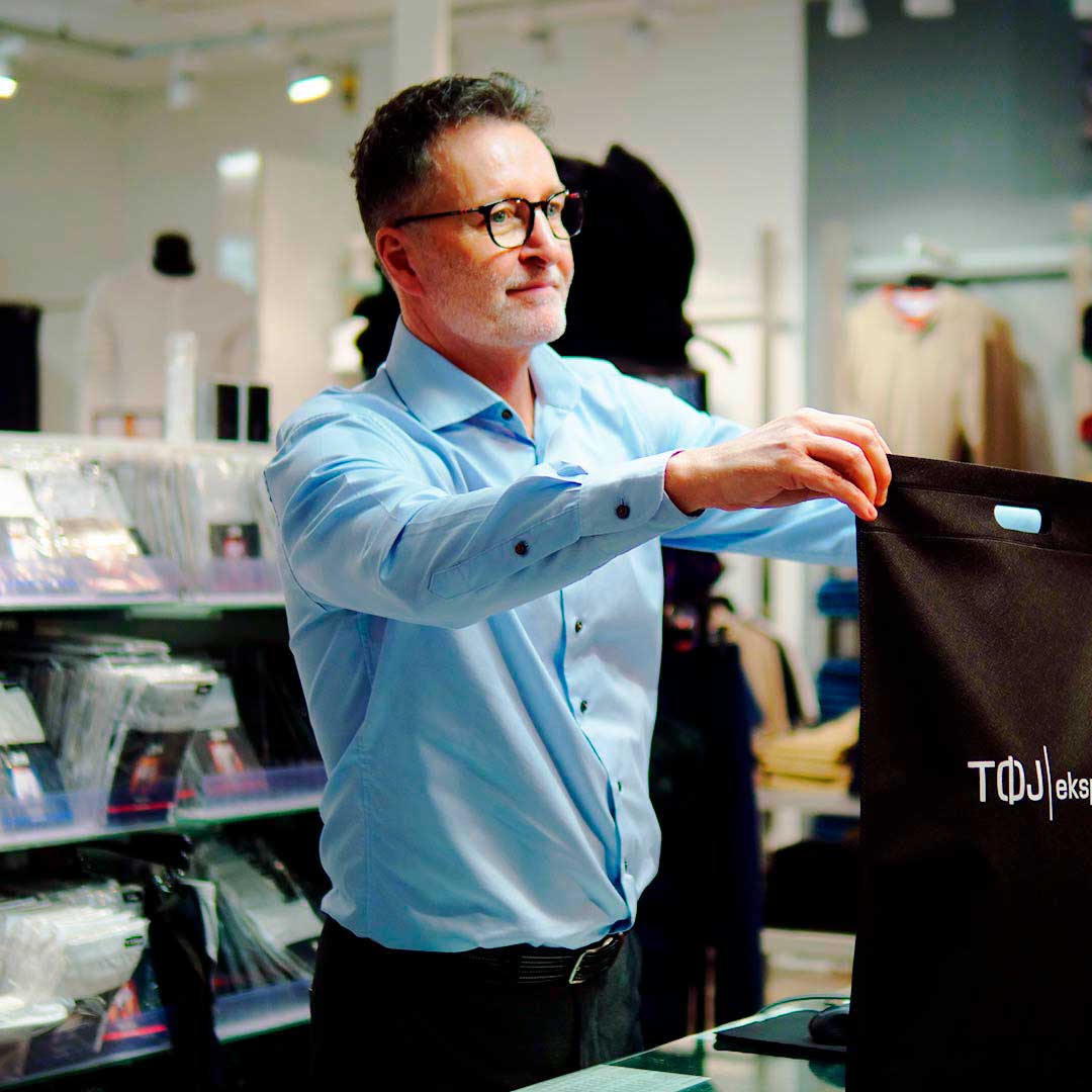 Medarbejder der er ved at give en pose til kunde i Tøjeksperten Glostrup